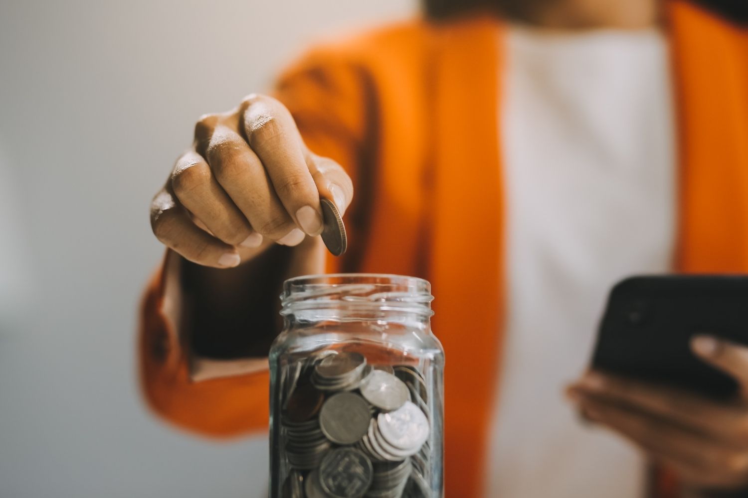 Man saving up coins in a jar - restaurant bookkeeping